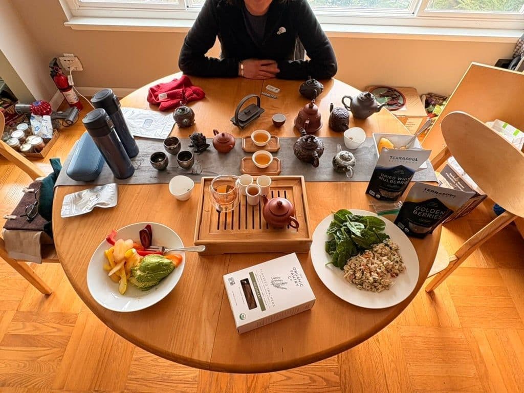 An overhead view of a full gongfu tea spread with cups, pots, and food